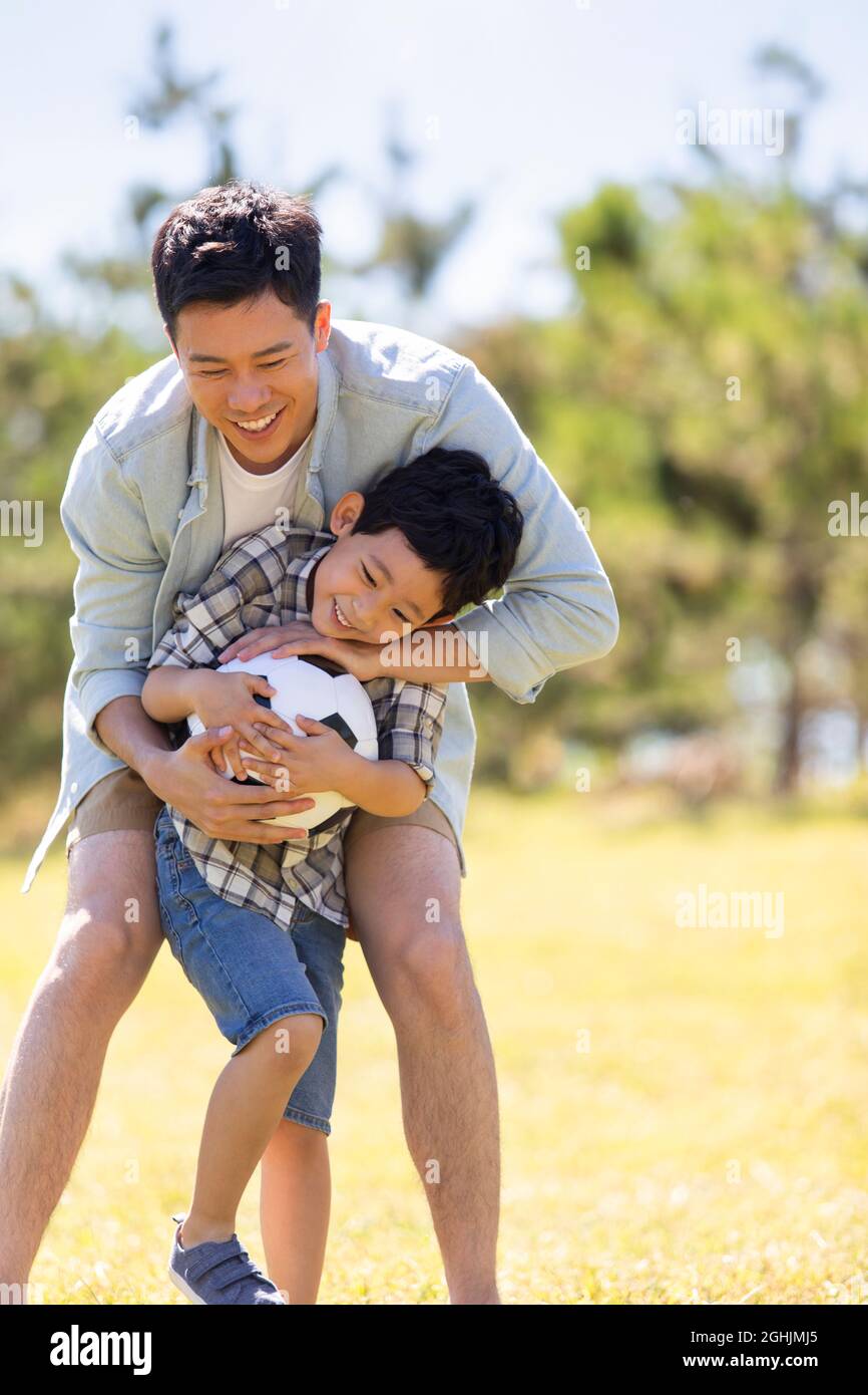 Happy father and son playing football in park Stock Photo - Alamy