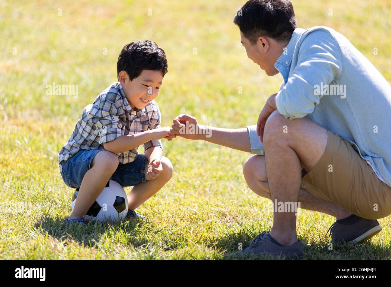 Happy father and son playing football in park Stock Photo - Alamy