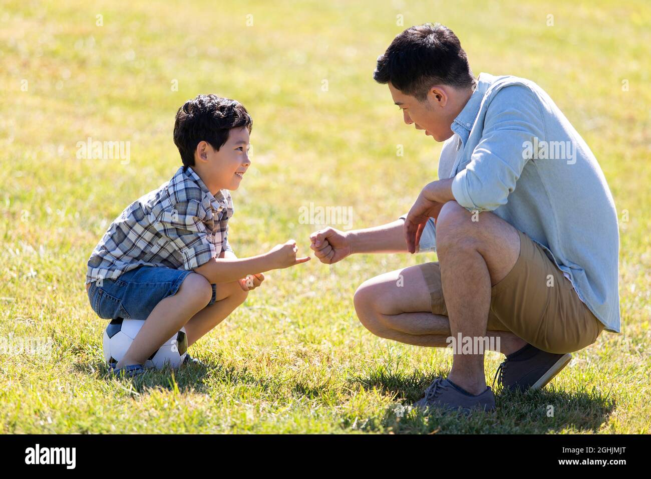 Happy father and son playing football in park Stock Photo - Alamy