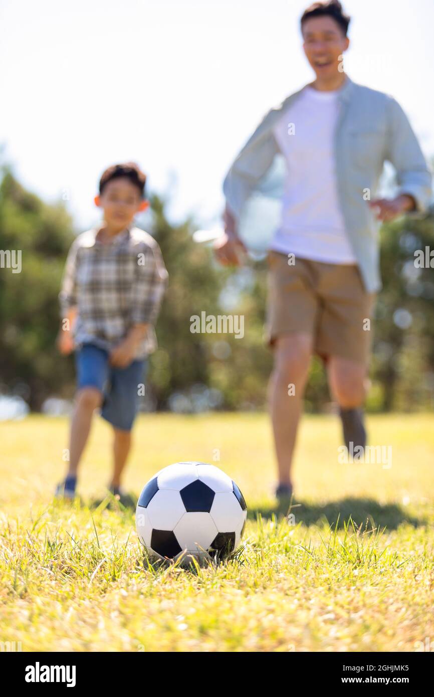 Happy father and son playing football in park Stock Photo - Alamy