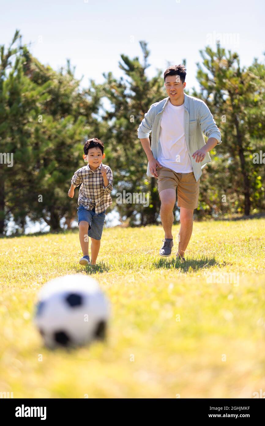 Happy father and son playing football in park Stock Photo - Alamy
