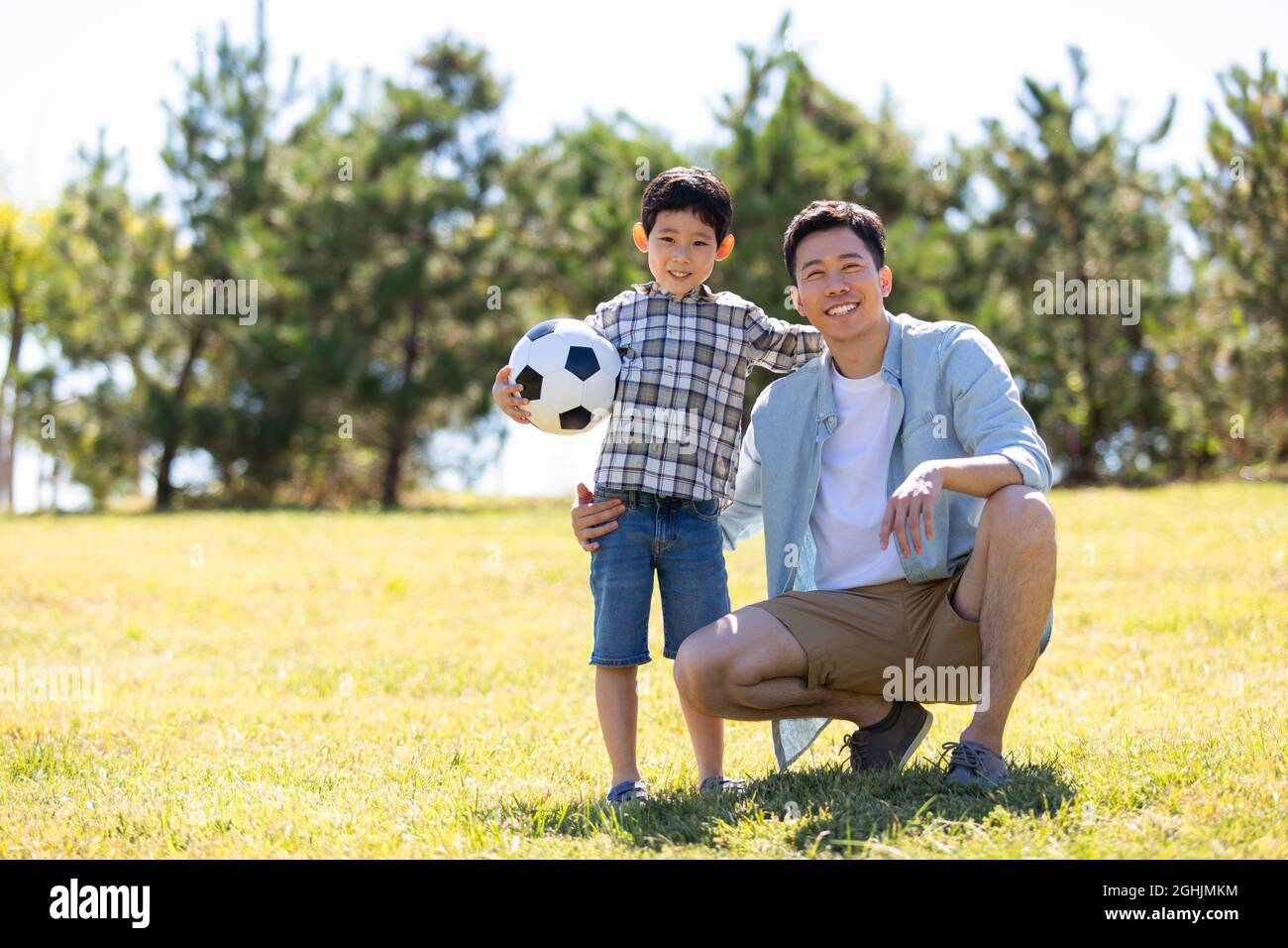 Happy father and son playing football in park Stock Photo - Alamy