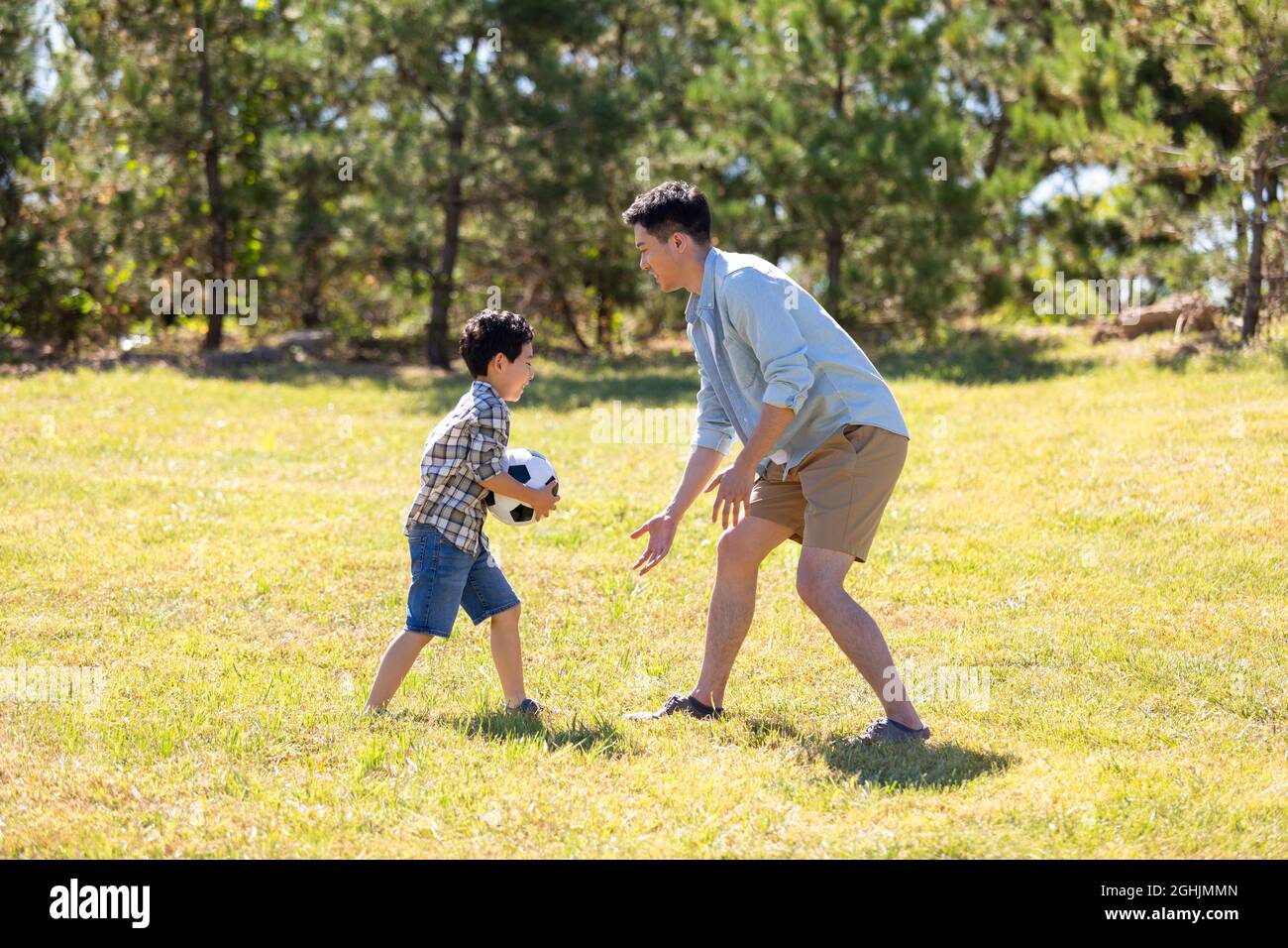 Happy father and son playing football in park Stock Photo - Alamy