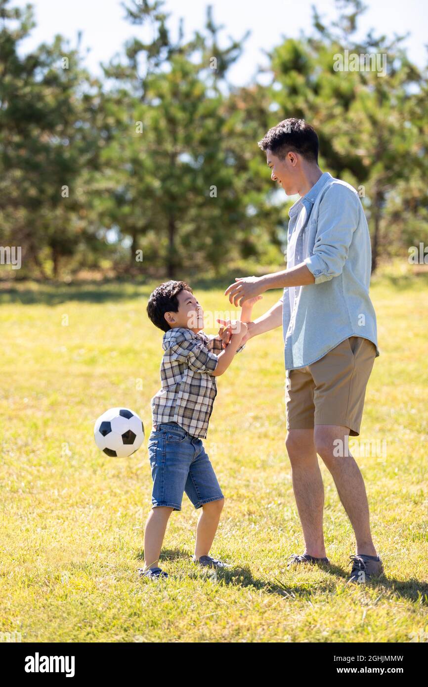 Happy father and son playing football in park Stock Photo - Alamy