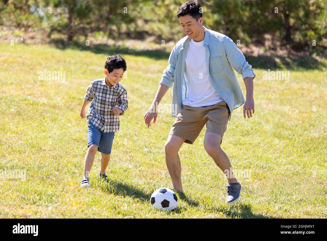 Happy father and son playing football in park Stock Photo - Alamy