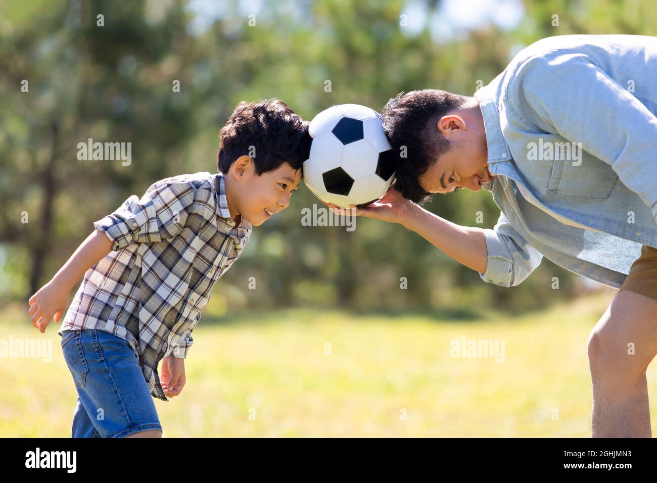 Happy father and son playing football in park Stock Photo - Alamy