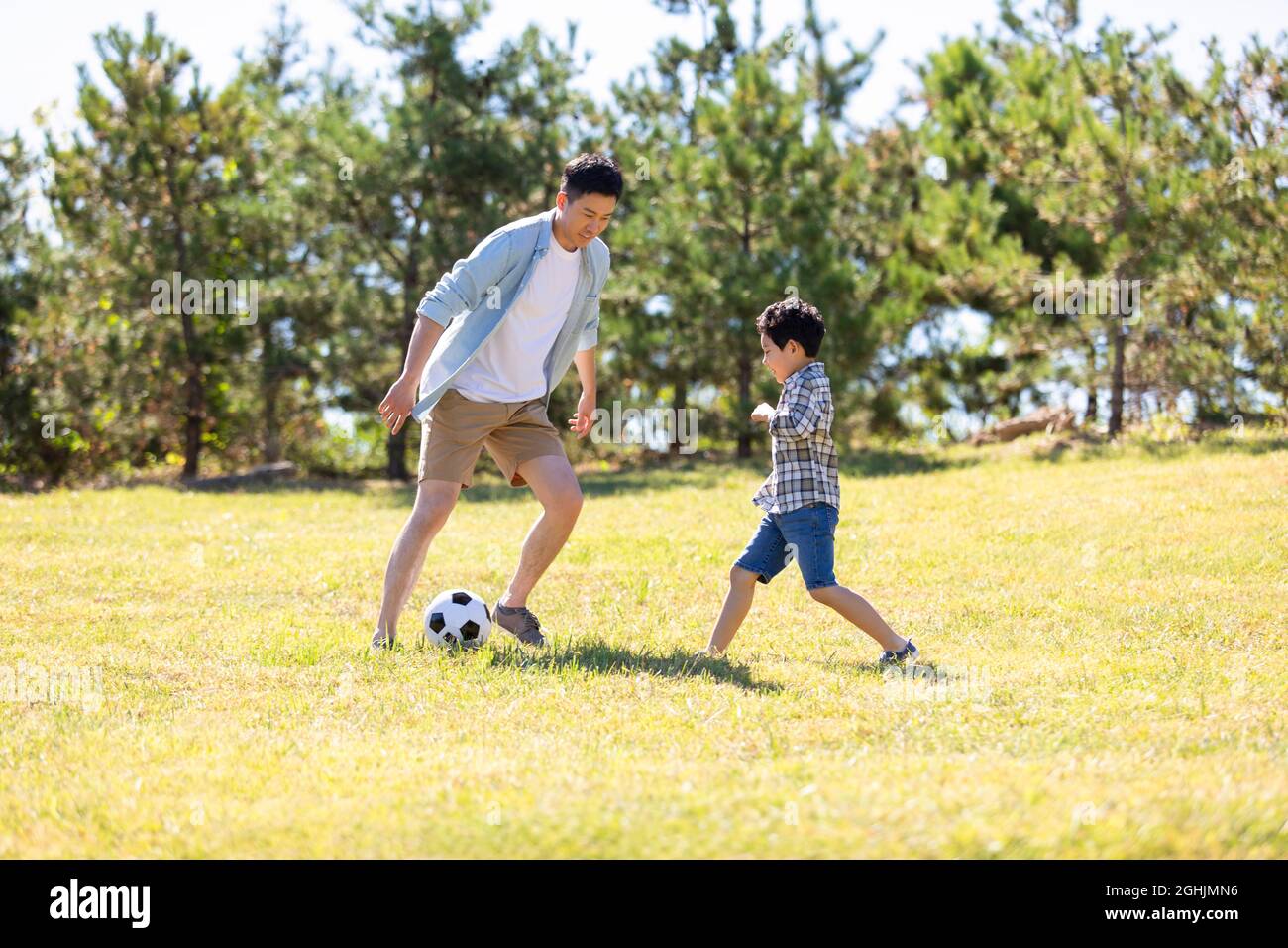 Happy father and son playing football in park Stock Photo - Alamy