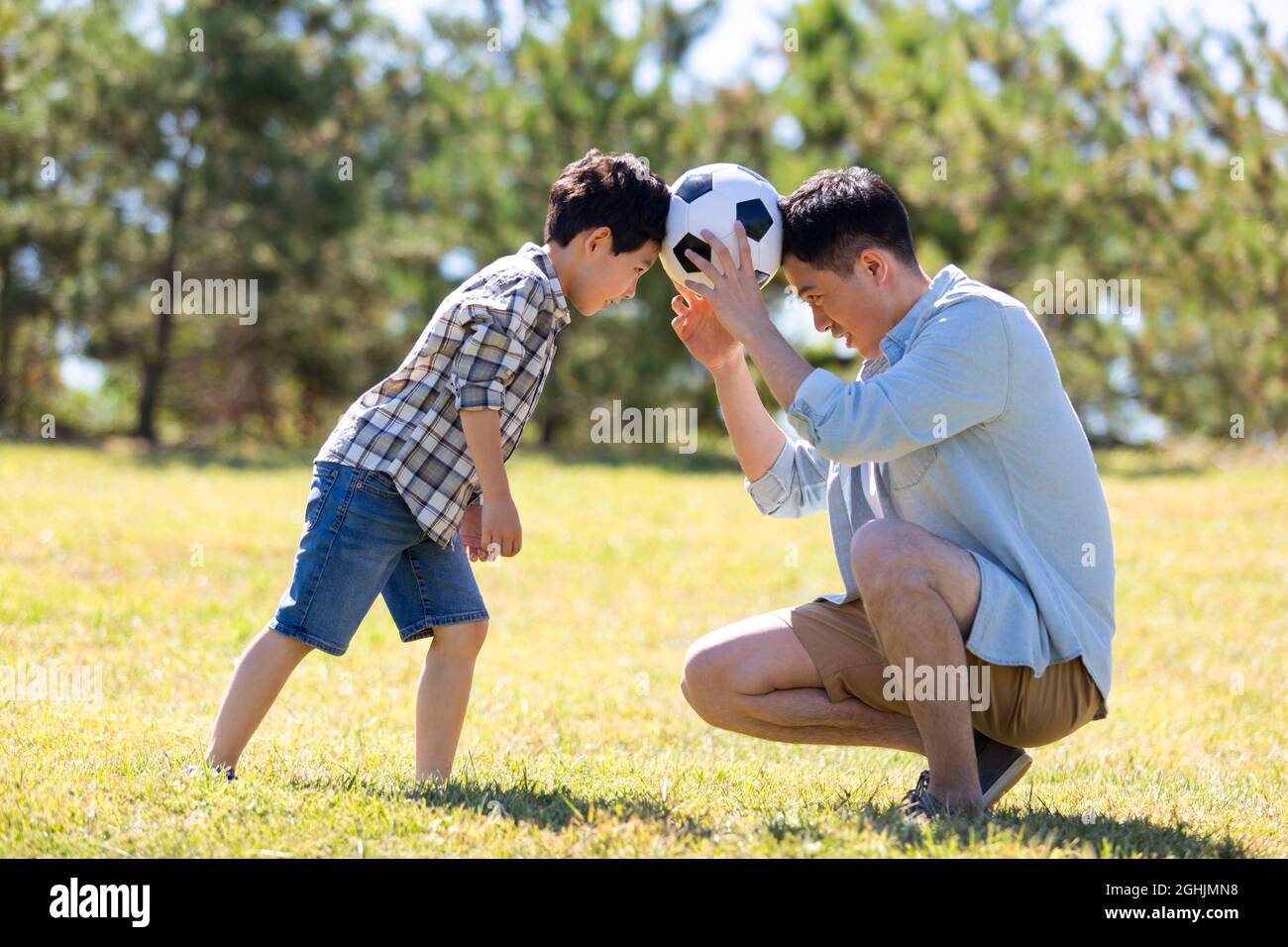Happy father and son playing football in park Stock Photo - Alamy