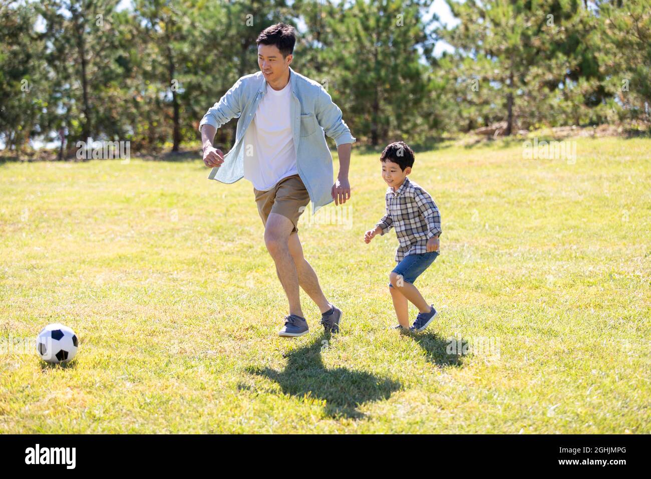 Happy father and son playing football in park Stock Photo - Alamy
