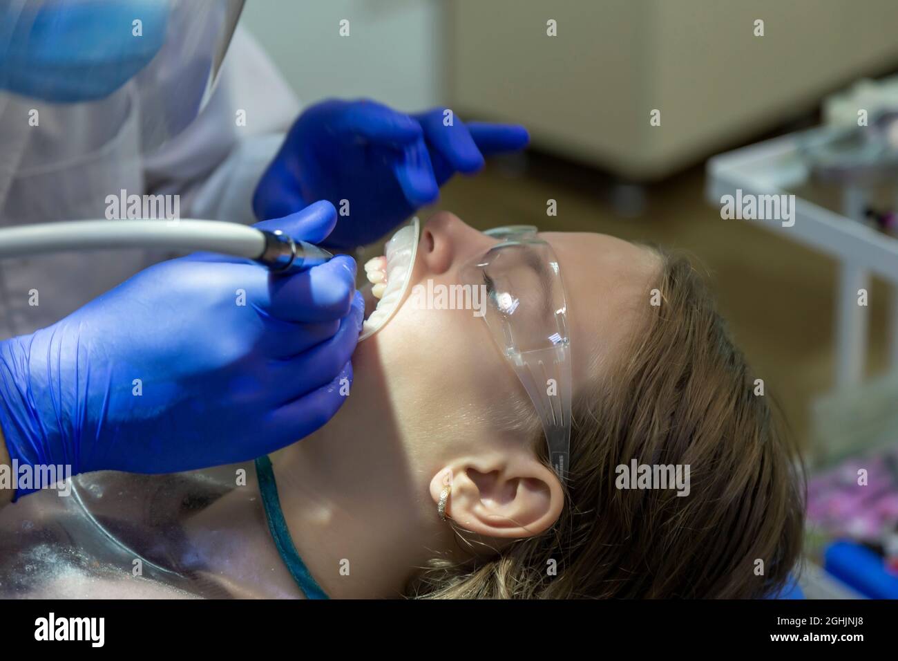 girl with glasses treats front teeth. Hands of a dentist. Tooth