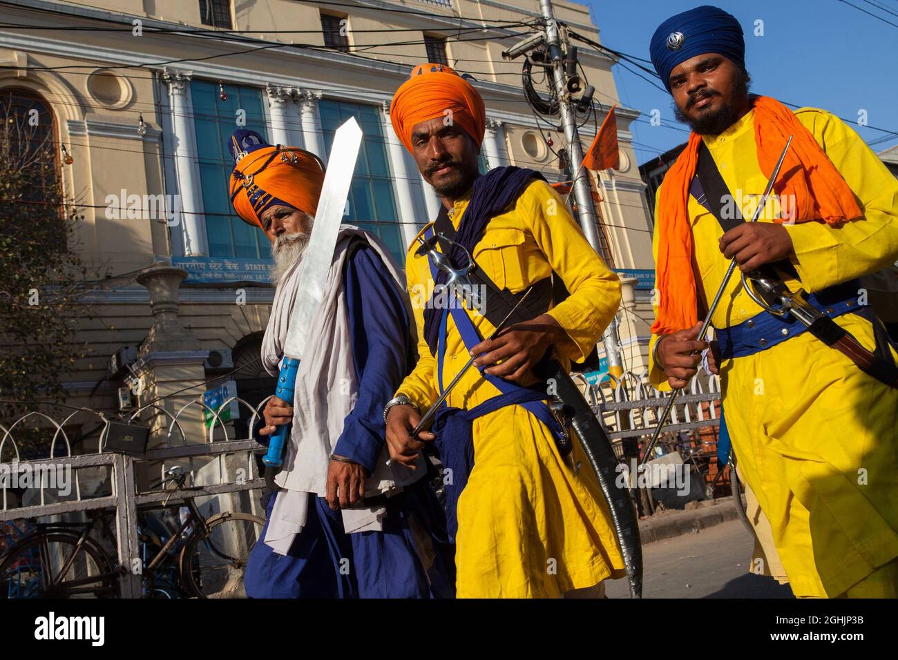 Sikh temple guards carry traditional kirpan & khanda swords in the old city of Delhi, India Stock Photo