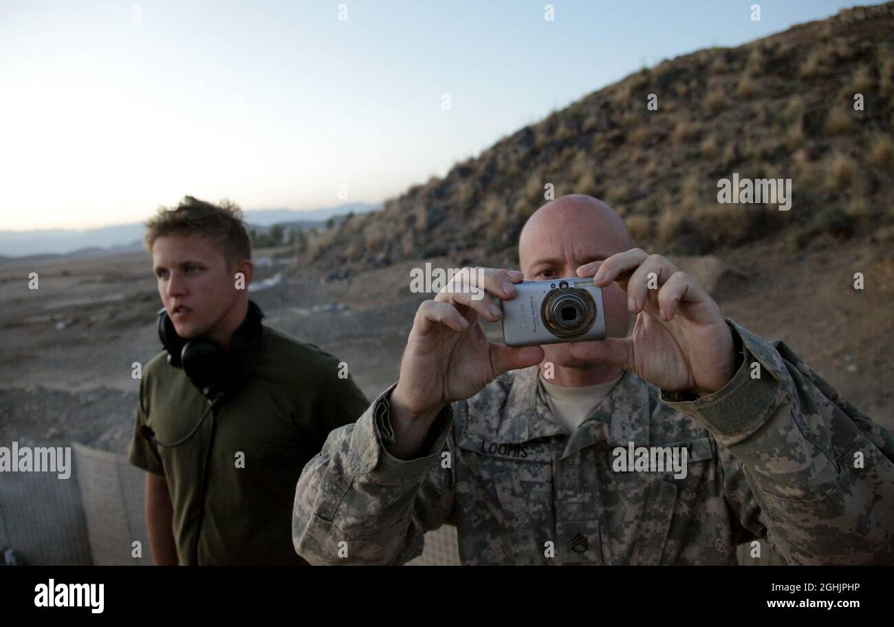 U.S. Army Staff Sgt. Jason Loomis, from Los Angeles, Calif., prepares to photograph 155 mm artillery rounds impacting on a nearby hillside at Combat Outpost Cherkatah, Khowst province, Afghanistan, Nov. 26, 2009. The artillery was fired by U.S. forces from Forward Operating Base Salerno during a test fire. Stock Photo