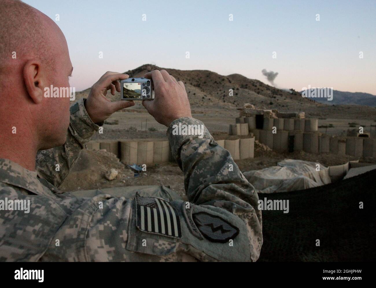 U.S. Army Staff Sgt. Jason Loomis, from Los Angeles, Calif., photographs 155 mm artillery rounds impacting on a nearby hillside at Combat Outpost Cherkatah, Khowst province, Afghanistan, Nov. 26, 2009. The artillery was fired by U.S. forces from Forward Operating Base Salerno during a test fire. Stock Photo