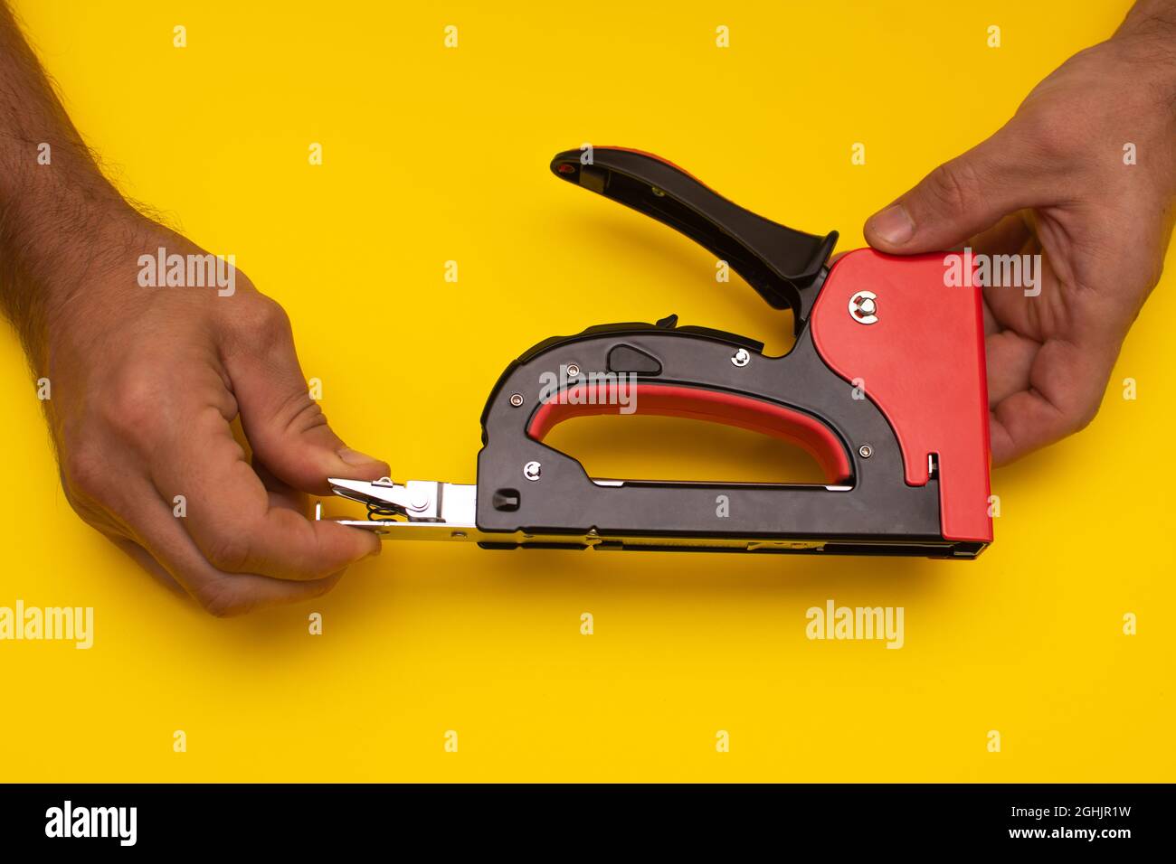 men's hands disassemble a construction stapler to fill it with staples