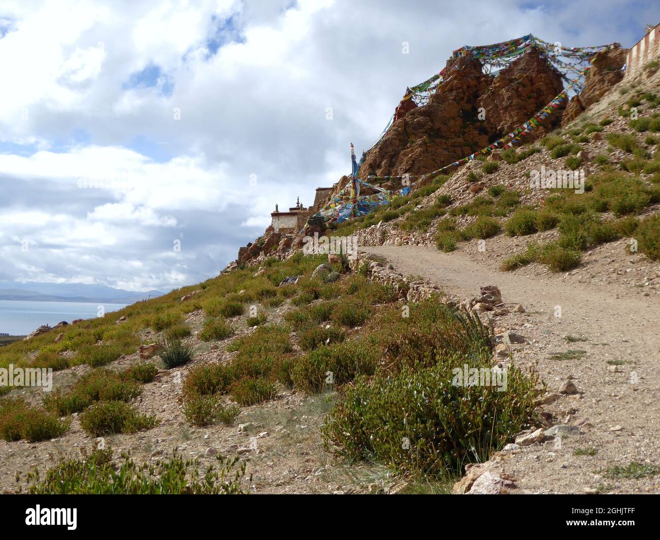 Dirt track leading to Chiu Gompa, a small Tibetan monastery built into the cliffs of a steep red-colored hill on the shores of Lake Manasarovar, Tibet Stock Photo