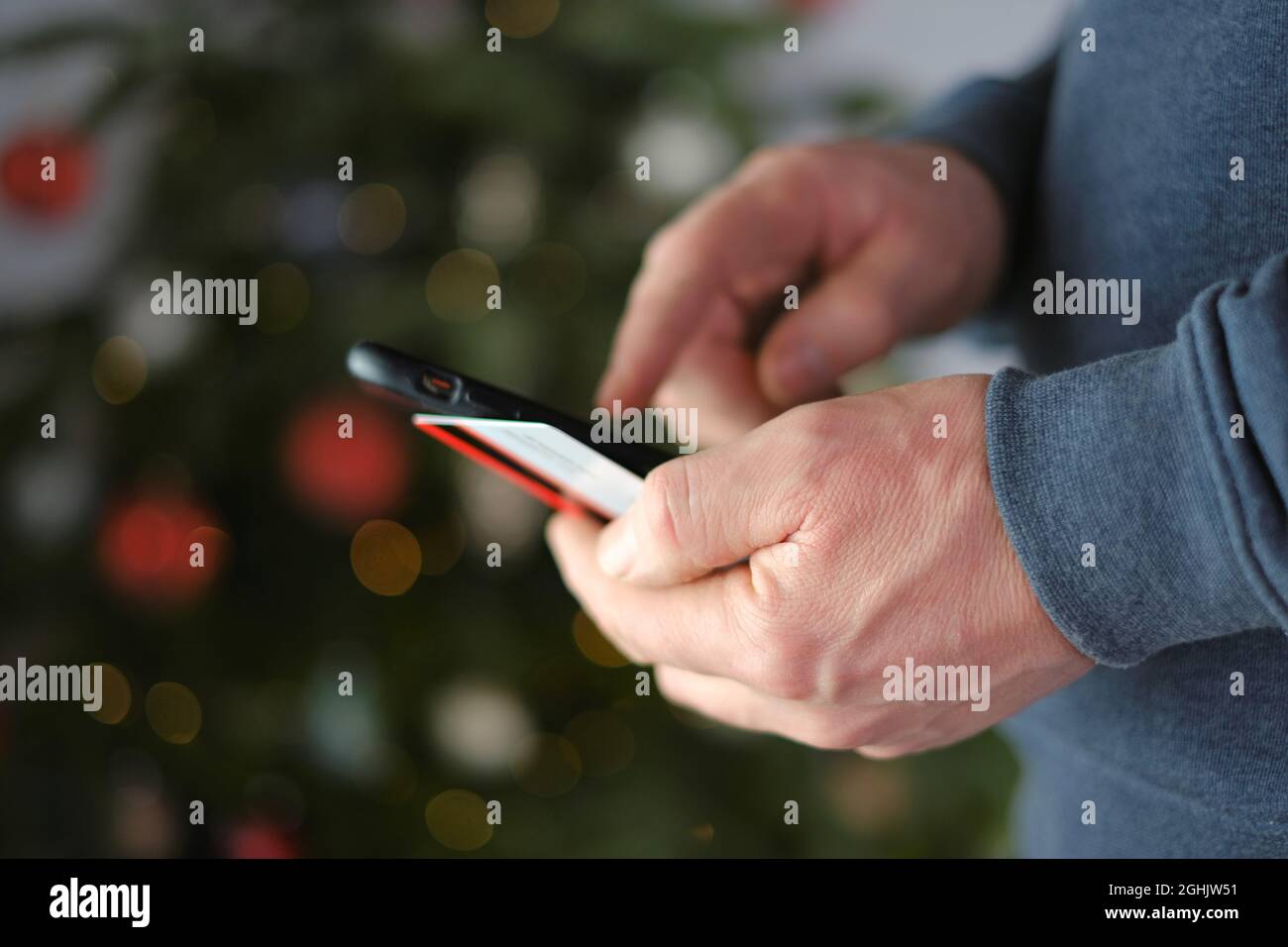 online shopping. Christmas and New Year shopping.Buying holiday gifts. Credit card and mobile phone in hands on shining Christmas tree background. Stock Photo