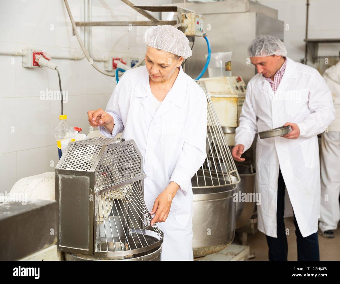 Bakers controlling dough making in kneading machine Stock Photo