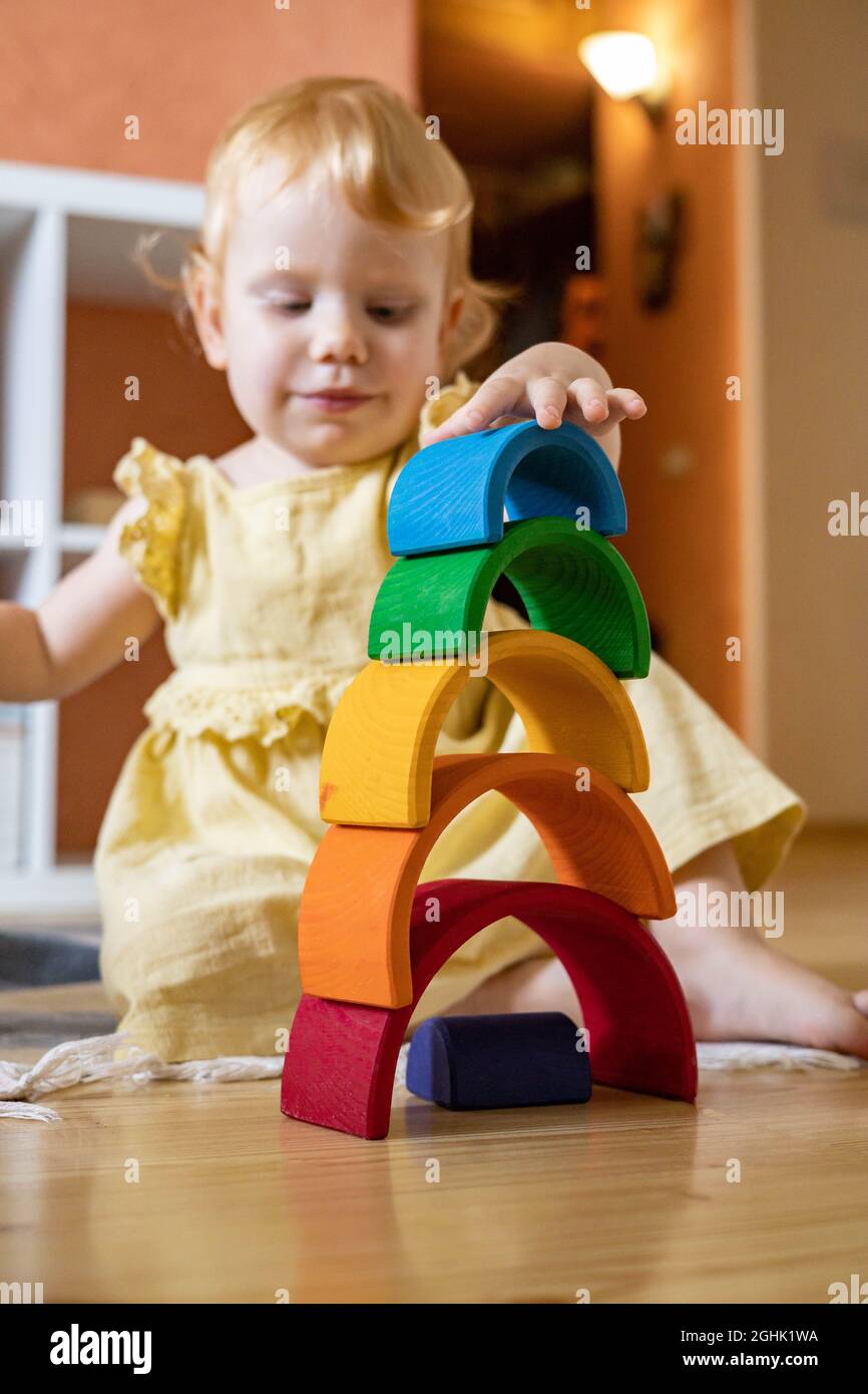 Baby girl in dress stacking rainbow arch block construction building ...