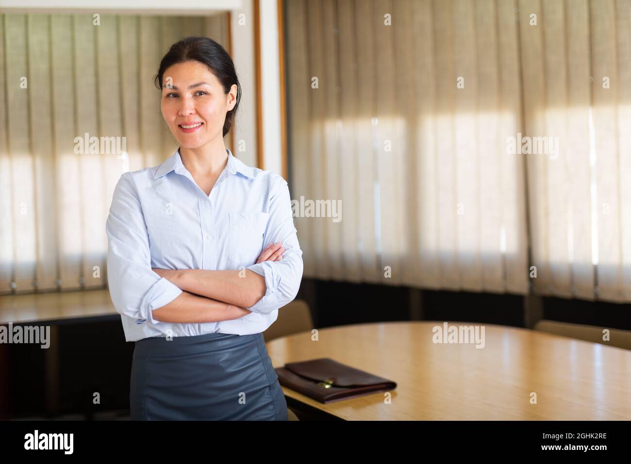 Successful business woman standing with arms crossed in office Stock ...