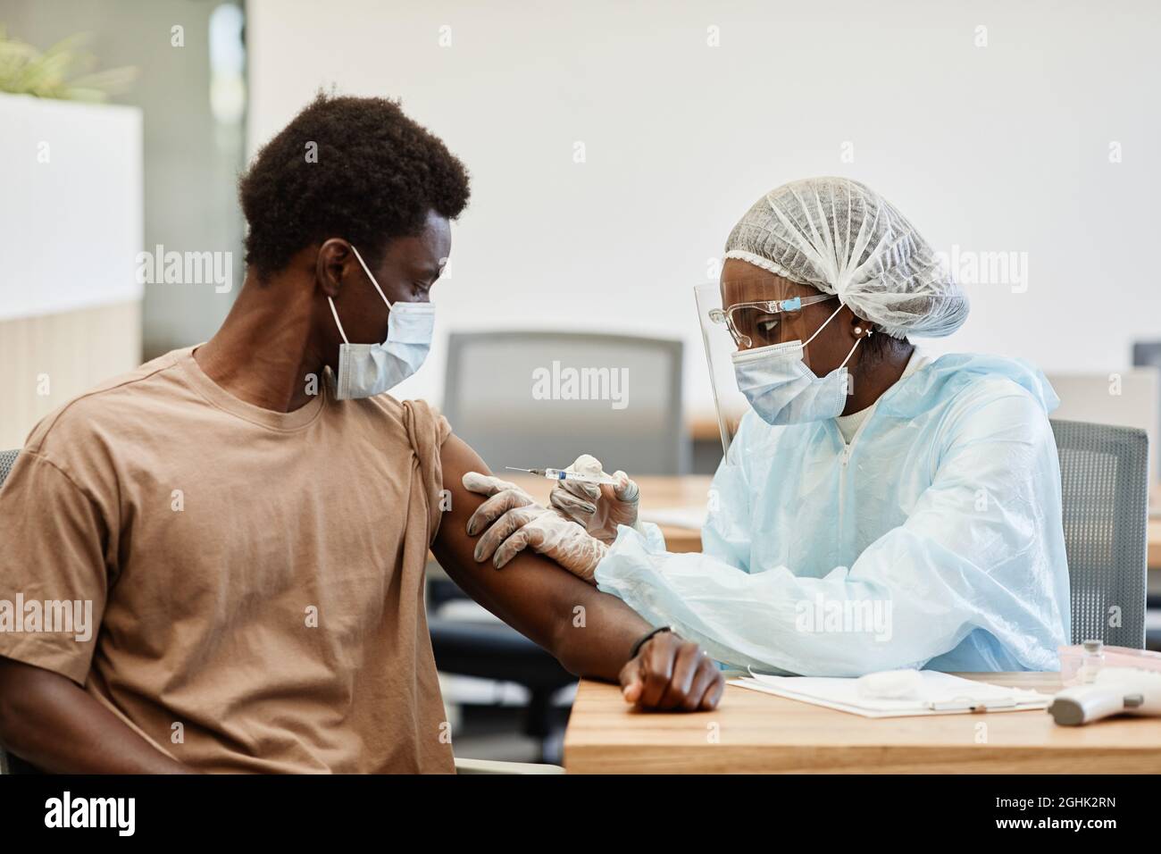 Young African-American man getting second shot of COVID-19 vaccine in hospital Stock Photo