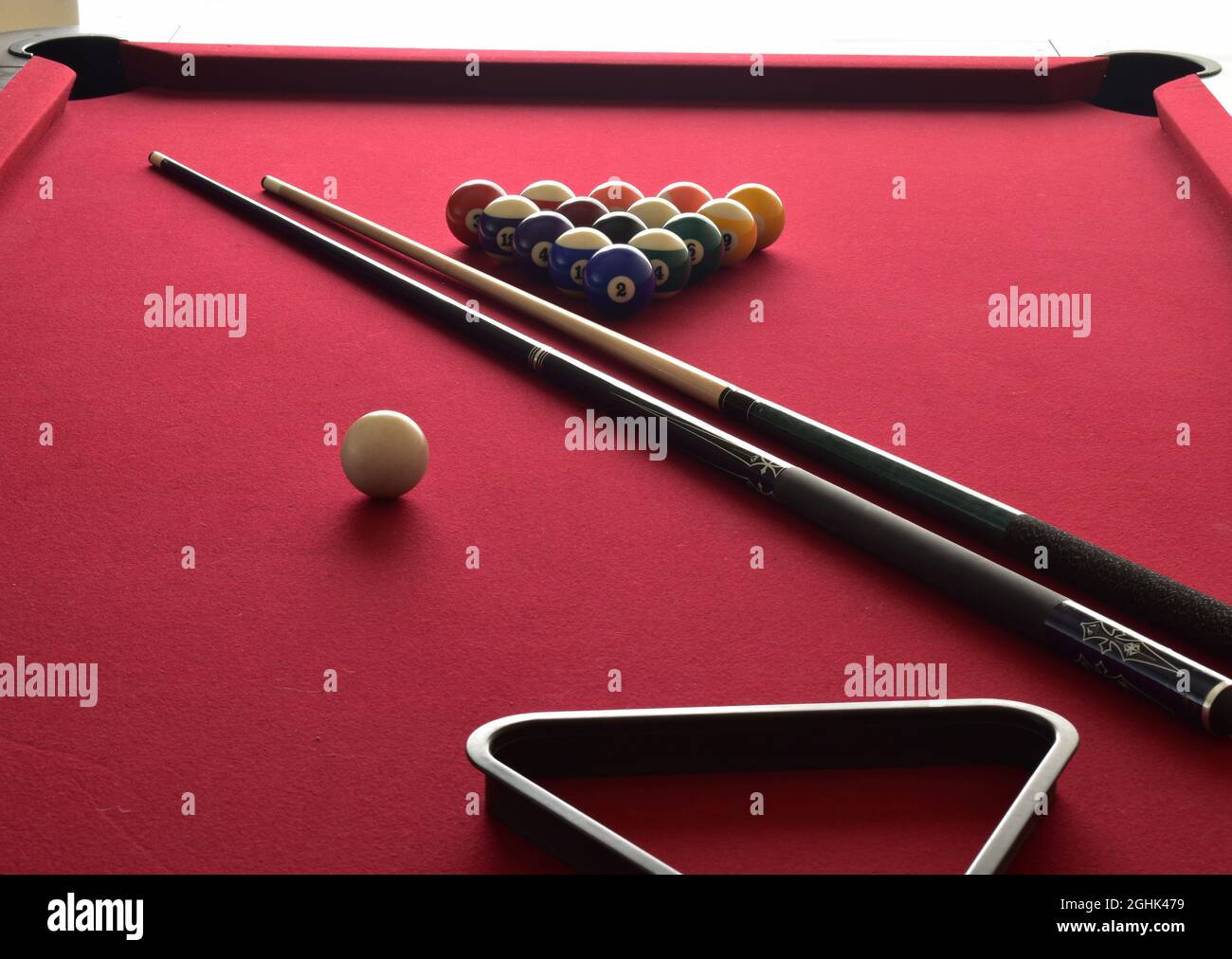 Billiard balls on a red pool table with two cues, ball rack and cue ball Stock Photo