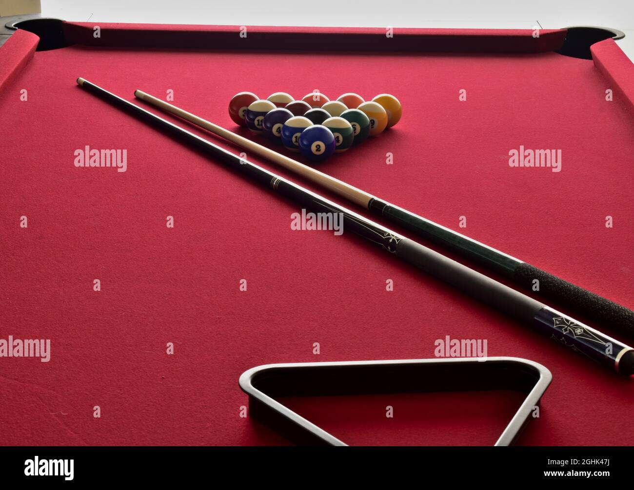 Billiard balls on red felt pool table with cues and black rack Stock Photo
