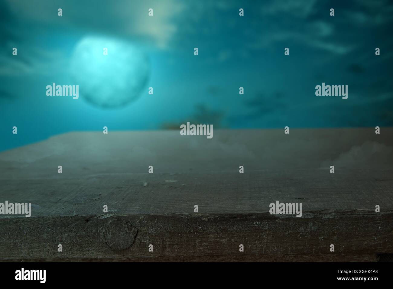 Wooden table with a full moon with dark cloudscapes on the night ...