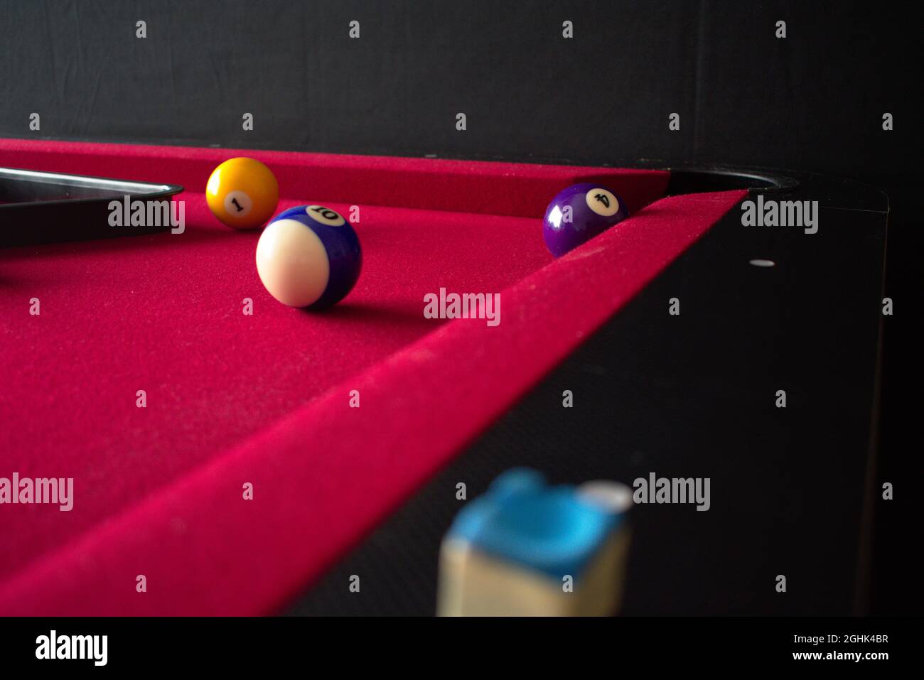 red felt pool table with colored billiard balls, ball rack and cue