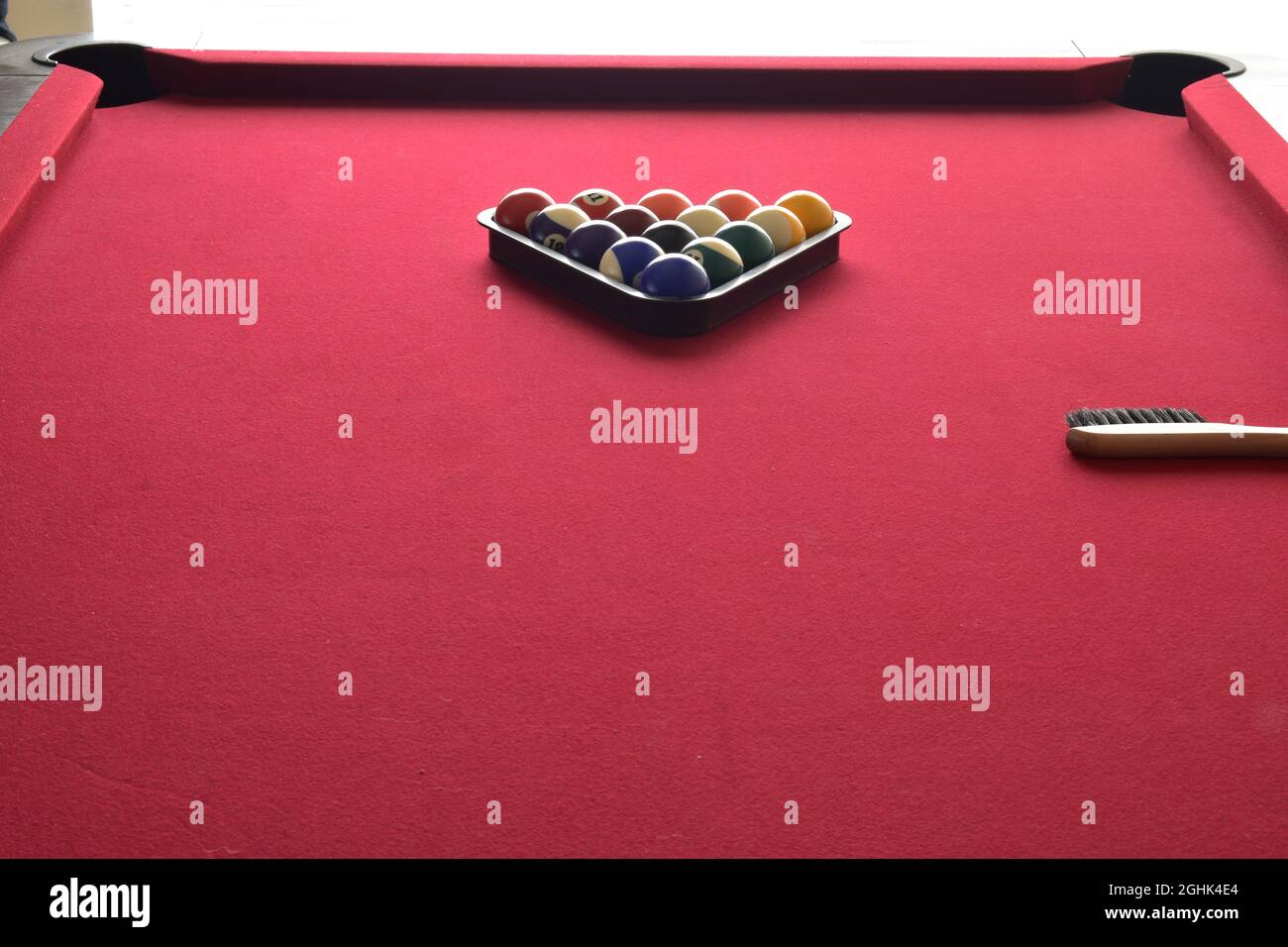 billiard balls in a black ball rack on a red top pool table Stock Photo