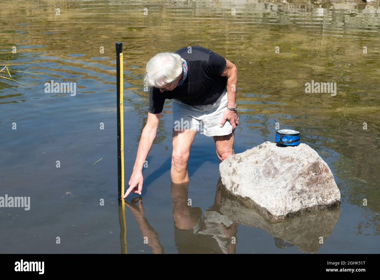 Man pointing to low lake level in small reservoir, Oregon, USA Stock Photo