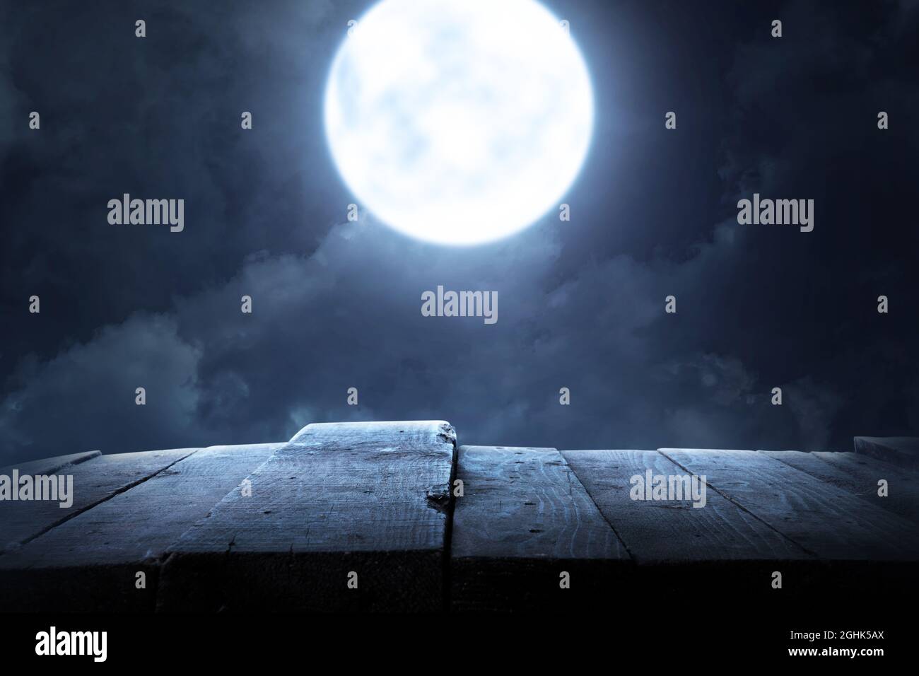 Wooden table with a full moon with dark cloudscapes on the night ...