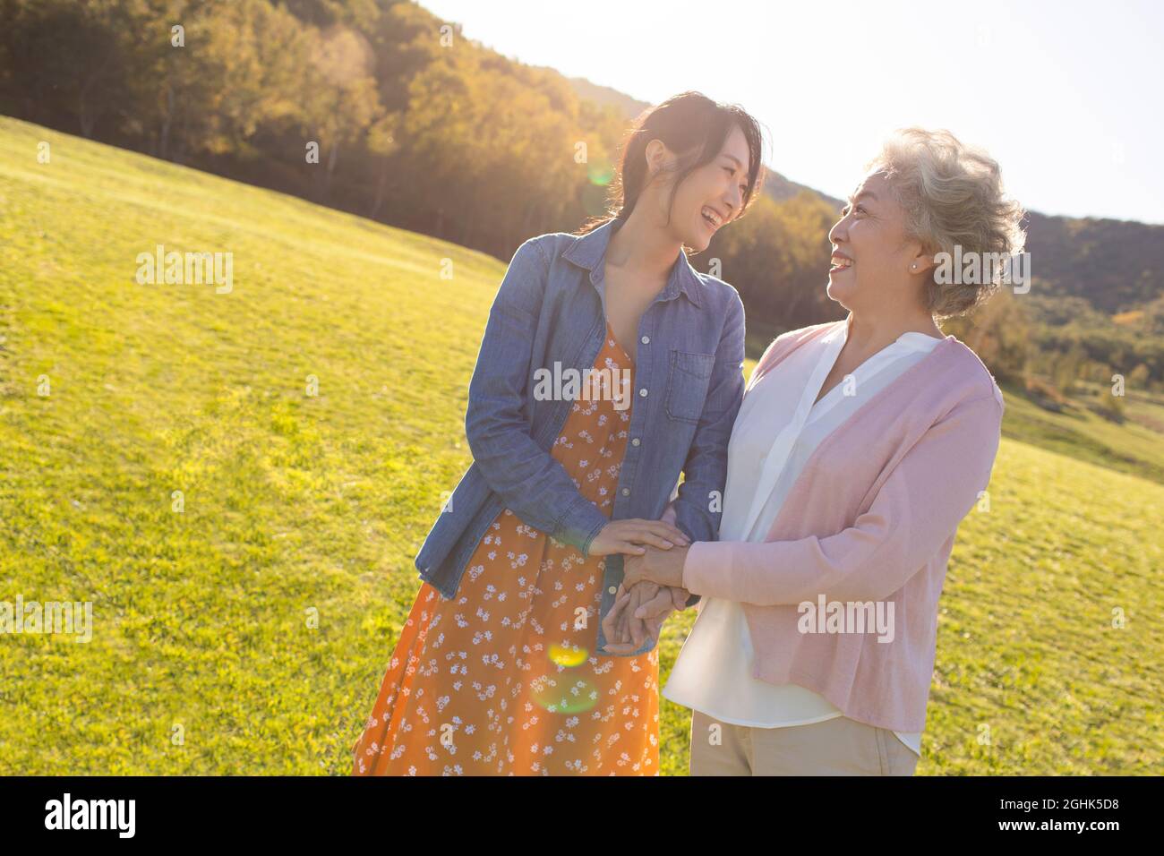 Happy mother and daughter relaxing on meadow Stock Photo