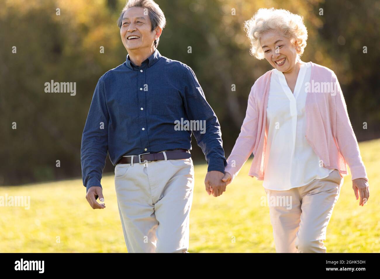Happy senior couple holding hands walking Stock Photo - Alamy
