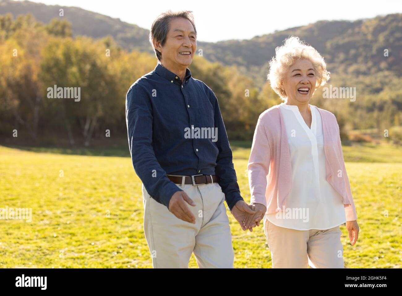 Happy senior couple holding hands walking Stock Photo - Alamy