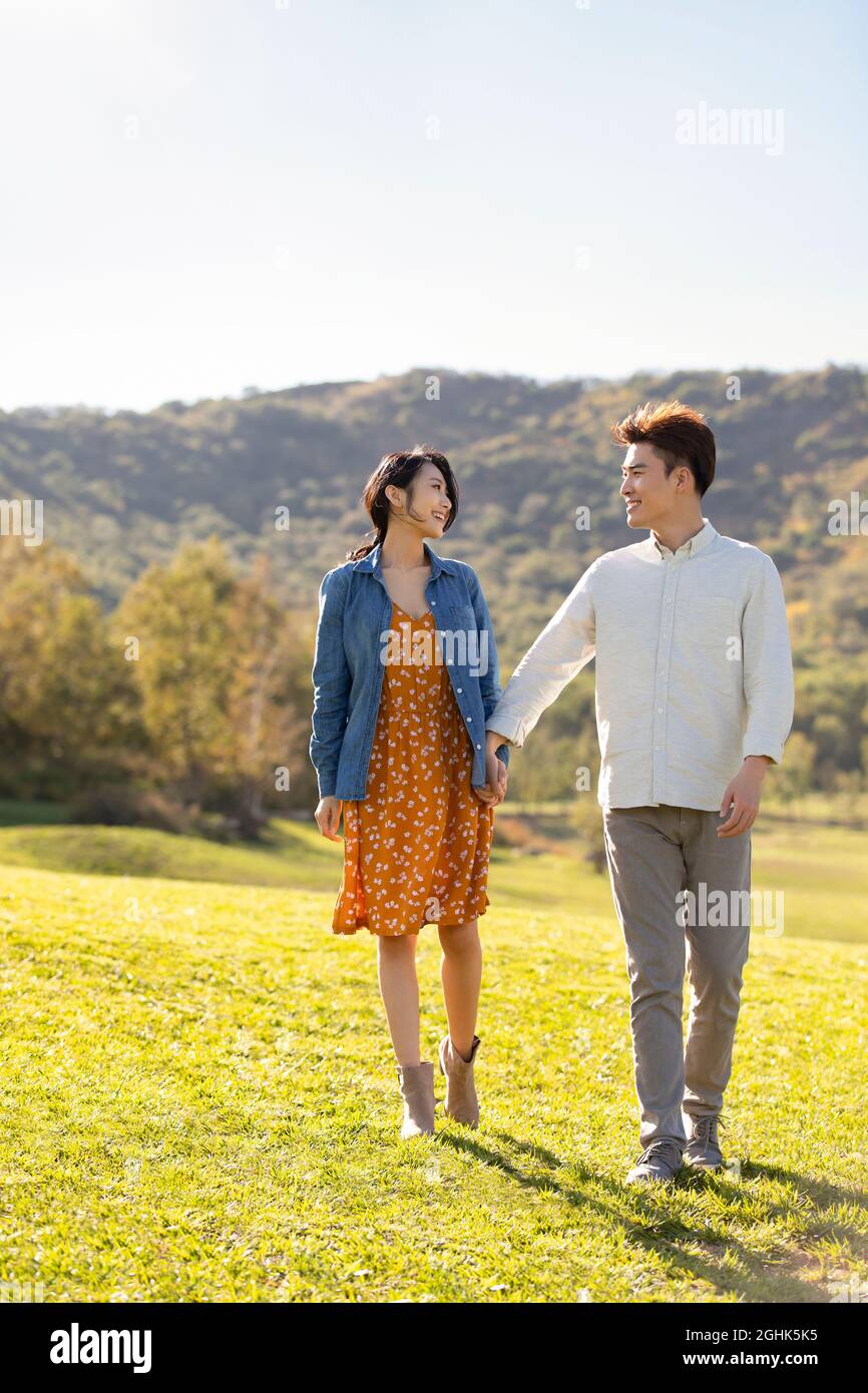 Happy young couple holding hands walking Stock Photo - Alamy