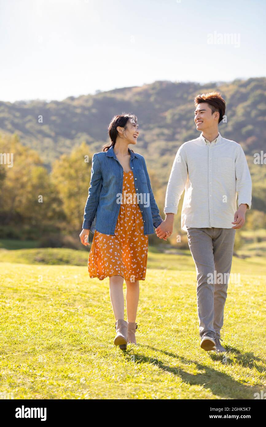 Happy young couple holding hands walking Stock Photo - Alamy