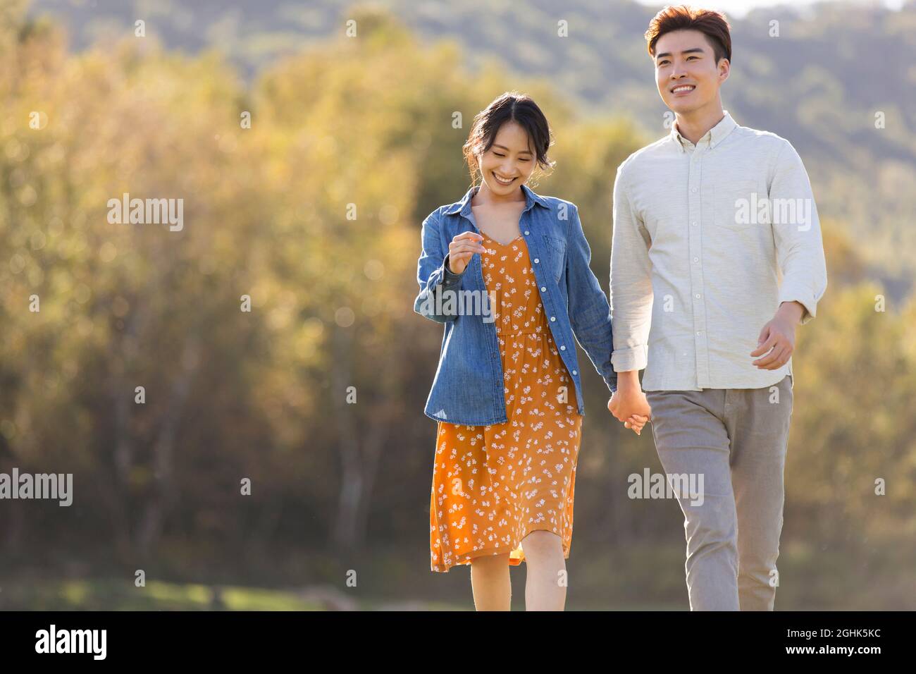 Happy young couple holding hands walking Stock Photo - Alamy