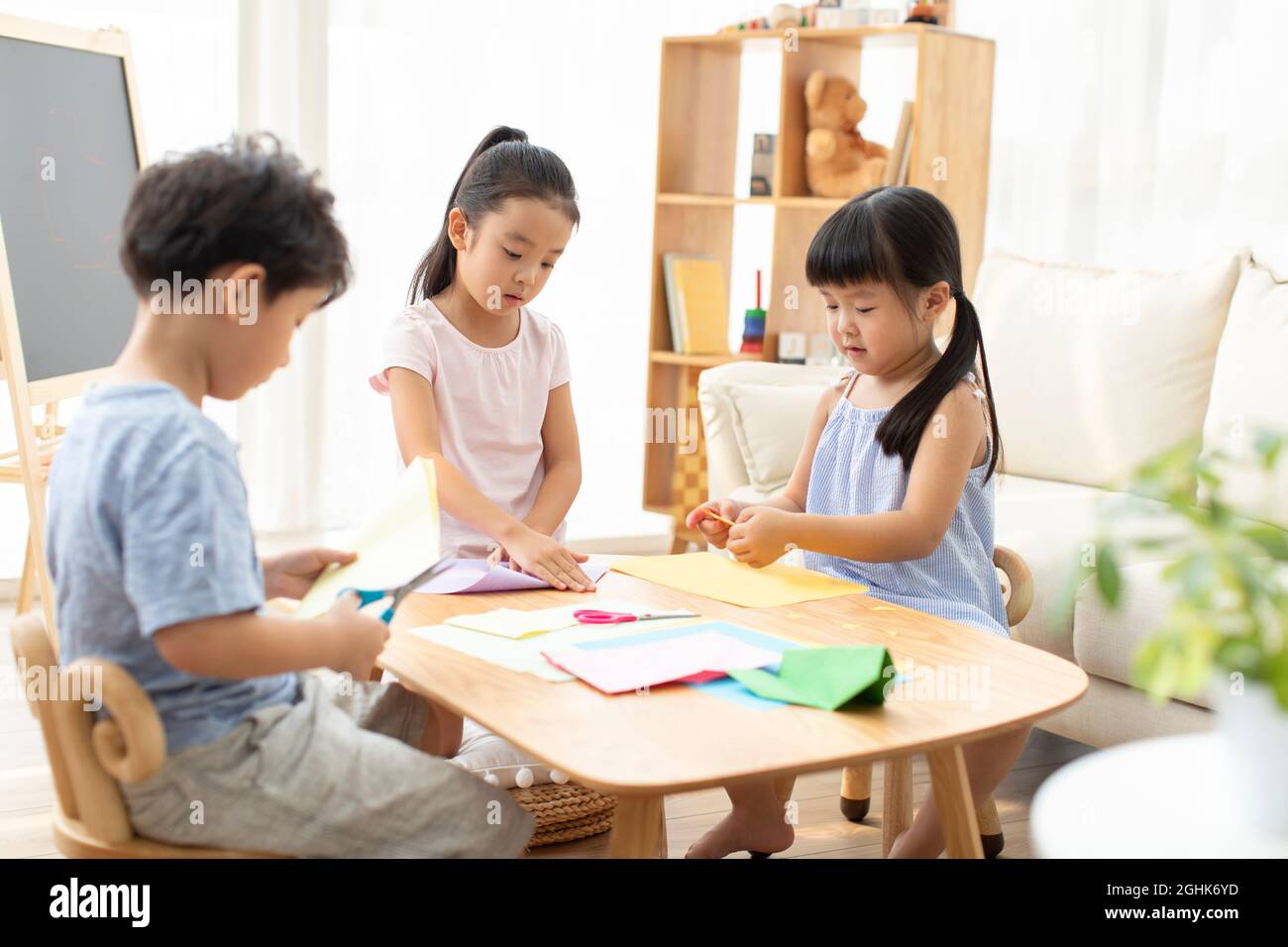 Child Using Paper Cute children doing paper craft in living room Stock Photo - Alamy