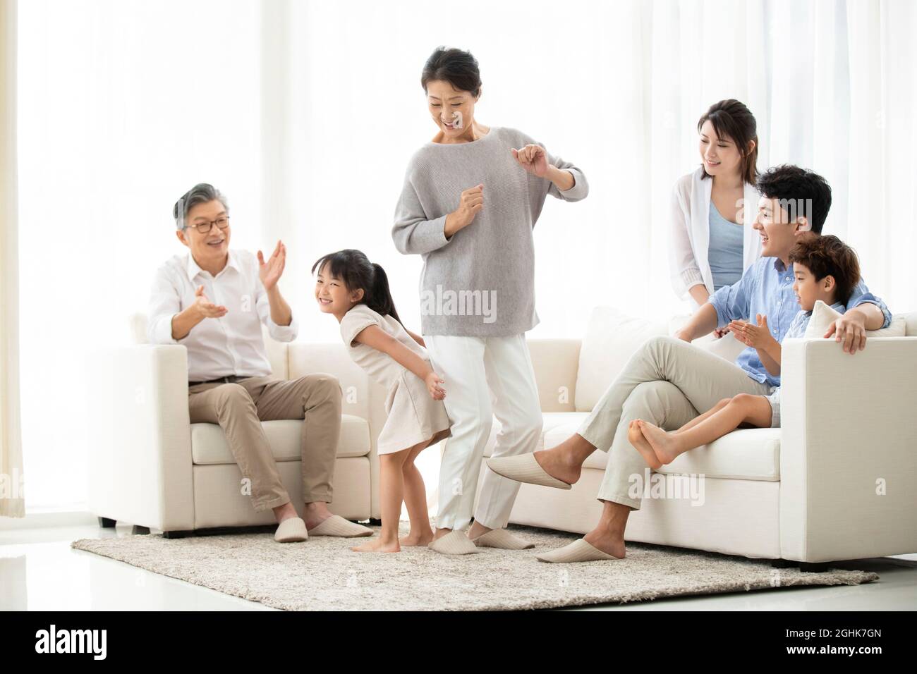 Cute girl and grandmother performing in living room Stock Photo