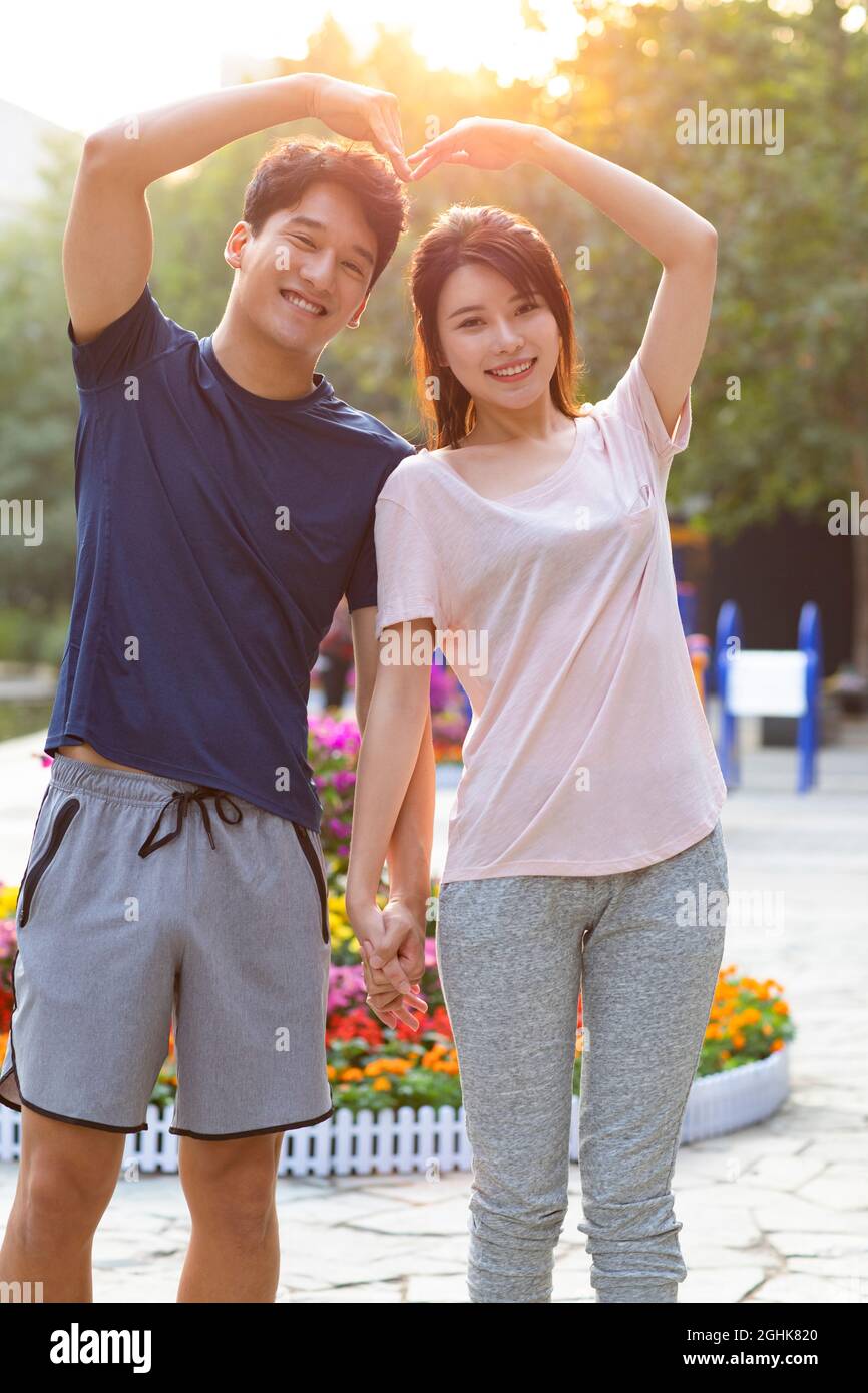 Cheerful young couple making heart shape with their hands Stock Photo ...