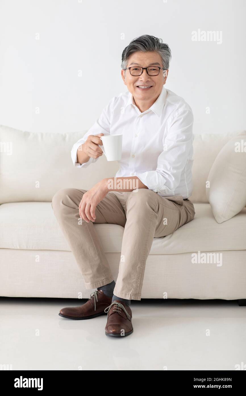 Cheerful senior man drinking coffee at home Stock Photo