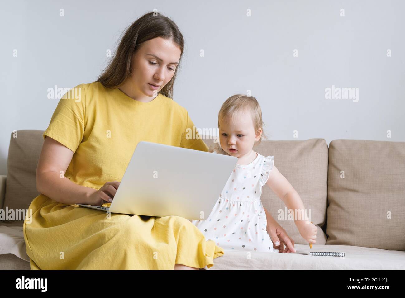 Curious child looking at mother laptop display. Mother using gadgets for baby entertainment Stock Photo