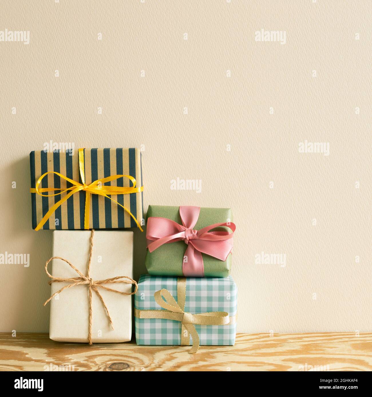 Stack of gift boxes on wooden table. beige wall background Stock Photo