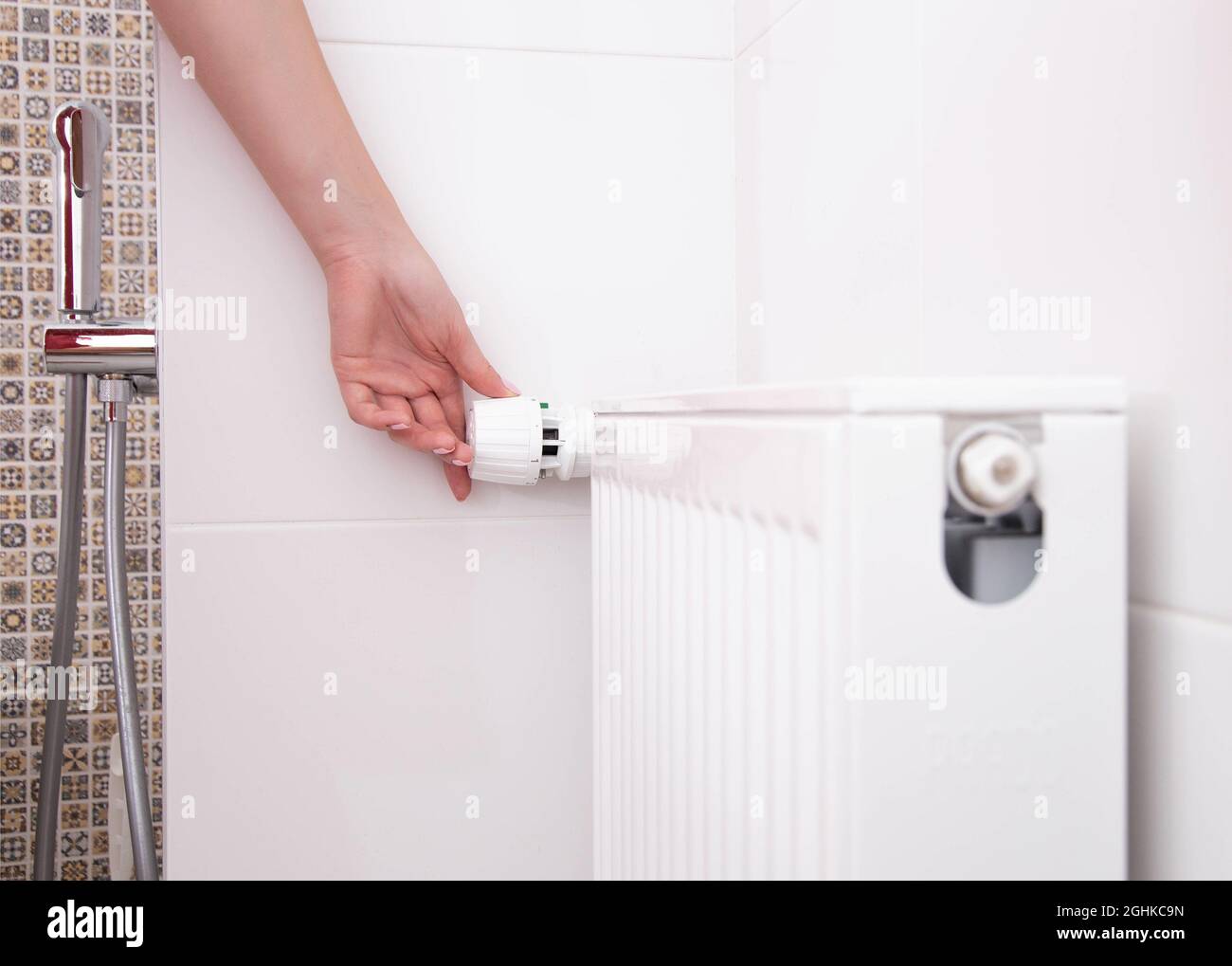 the woman turns on the heating radiator in the bathroom with a