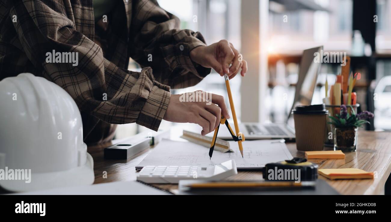 Architect or Engineer working with compasses and blueprints for architectural plan,engineer sketching a construction project concept Stock Photo