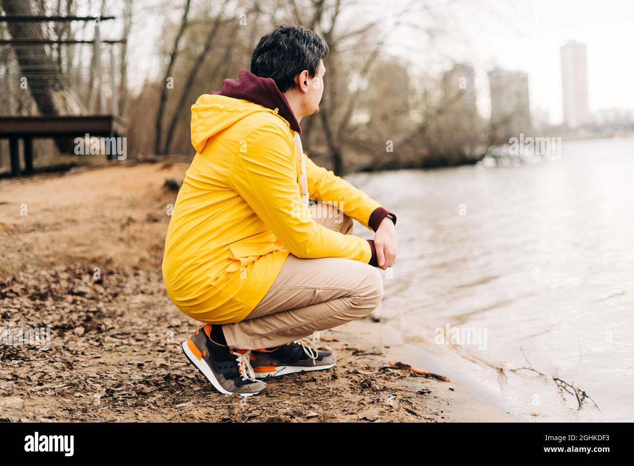 Young man sit on the shore of the lake outdoors over autumn park background Stock Photo