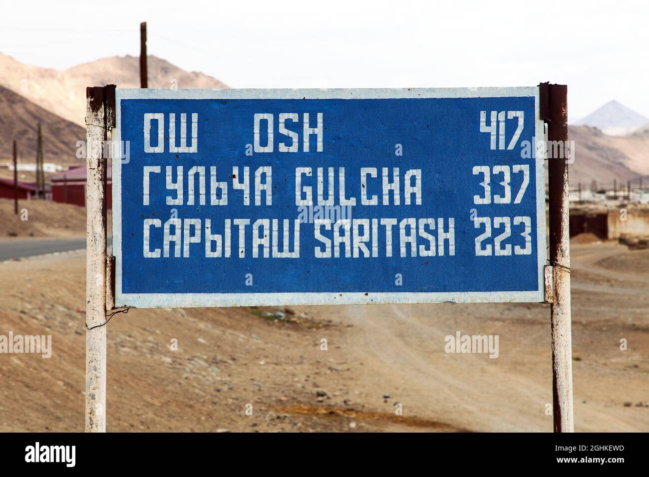 Signpost with distance to three town in cyrillic and roman - 'Osh' 'Gulcha' and 'Saritash' - Pamir highway or Pamirskij trakt, Kyrgyzstan and Tajikist Stock Photo