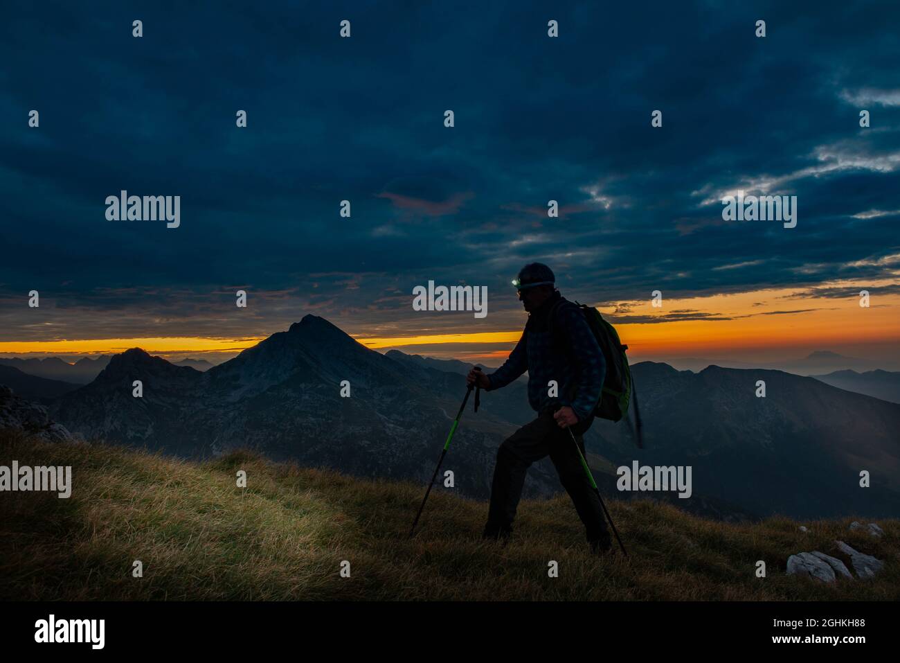 Hiker climbs to the top of the mountain at the first light of day Stock Photo