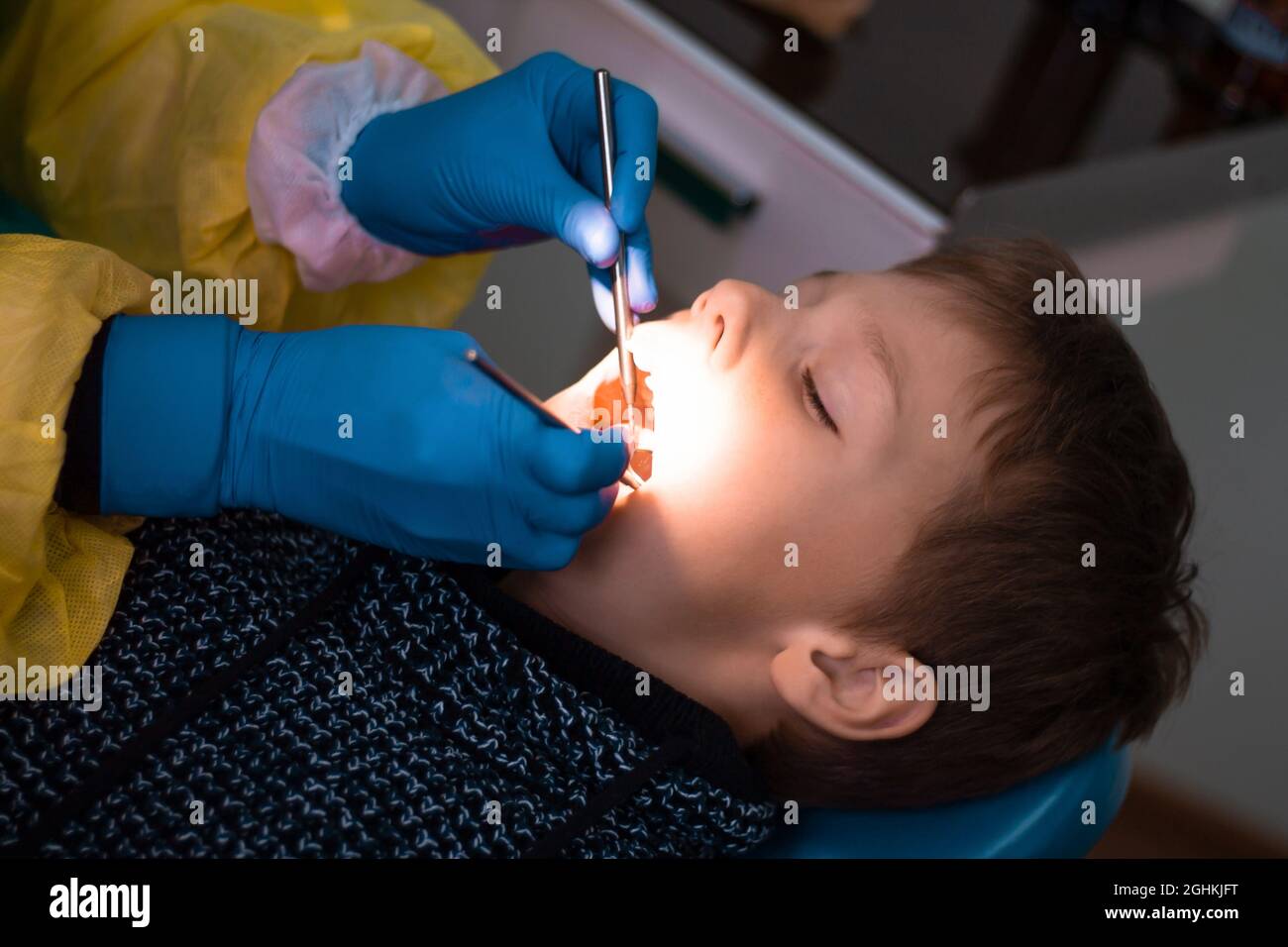 Boy 7-11 in the dentist's chair and the doctor's hands in blue gloves during dental check-up or dental treatment Stock Photo