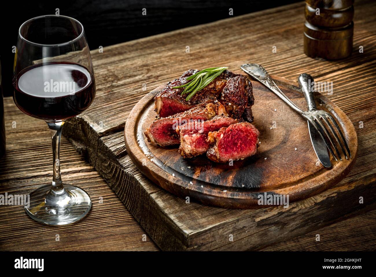 Grilled ribeye beef steak with red wine, herbs and spices on wooden ...